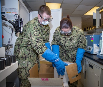 Military health personnel wearing face mask put vaccines into a freezer