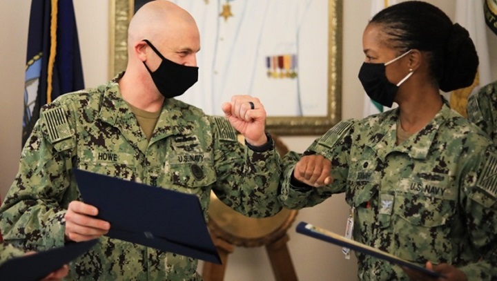 Image of Miliary health personnel wearing face mask bumping elbows.