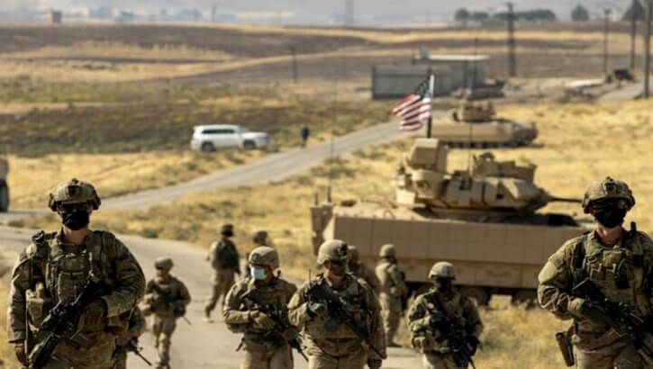 Image of Soldiers patrol in Syria in front of a Bradley tank.