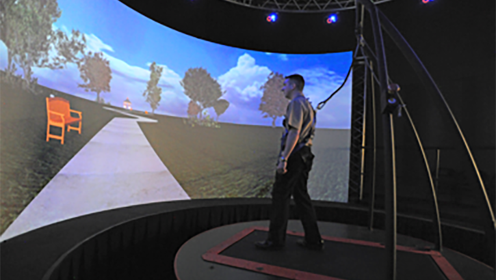 A person walks in front of a large virtual reality screen.