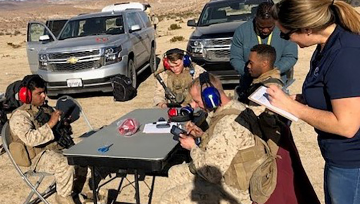 Image of Military personnel sitting at a table collecting data.