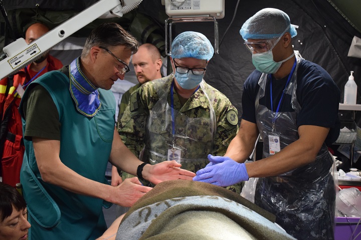 Navy Cmdr. Mark Lambert (center) and Navy Hospital Corpsman 2nd Class Amos Bogs (right), work with Capt. Peter Landell (left), Swedish Armed Forces, during a multinational medical drill, Cincu Military Base, Romania, during exercise Vigorous Warrior 19. (U.S. Air Force photo by 1st Lt. Andrew Layton)