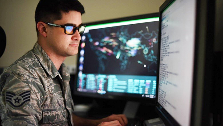 Soldier sitting in front of two computer monitors