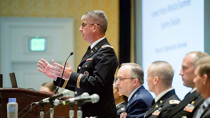 Image of Military personnel speaking in front of an audience at the Military Health Systems Research Symposium. Click to open a larger version of the image.