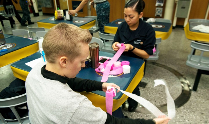 Navy Aviation Boatswain's Mate, Airman Sierra Clark (left), and Culinary Specialist Seaman Bielle Garcia, prepare decorations for a breast cancer awareness social aboard the U.S.S. John C. Stennis. 