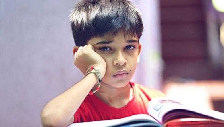 a young boy looking sad while reading a book 