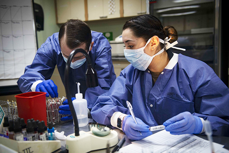 Image of Navy Petty Officer 2nd Class Cecil Dorse, left, and Navy Petty Officer 3rd Class Janet Rosas test blood samples aboard the Military Sealift Command hospital ship USNS Comfort while the ship is in New York City in support of the nation’s COVID-19 response, April 6, 2020. Photo By: Navy Petty Officer 2nd Class Sara Eshleman.