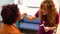 Breast Health Clinical Navigator and Nurse Carlie Berriri (R) administers a mouth swab test on a patient