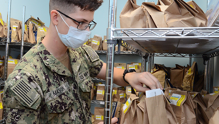Image of Military personnel wearing a face mask handling prescription refills at a pharmacy. Click to open a larger version of the image.