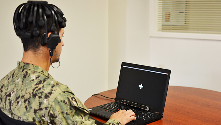Soldier sitting in front of a laptop with headphones on
