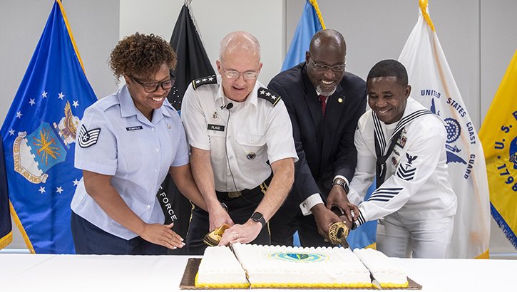 Image of Four DHA personnel, including DHA Director Place, center, cut a birthday cake with a sword to celebrate DHA's ninth birthday. Oct. 1, 2022.