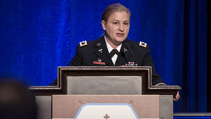 Image of U.S. Army Col Jennifer Stowe presents her research from behind a podium at the MHSRS meeting 2022. .