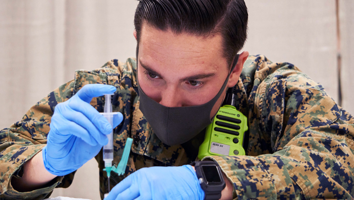 Image of Military personnel wearing a face mask preparing a COVID-19 vaccine.