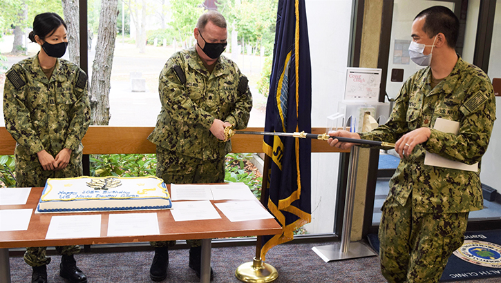 Image of Three military personnel wearing masks, in front of a sheet cake.