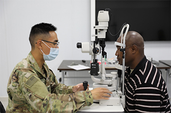 Military health personnel wearing a face mask giving an eye exam