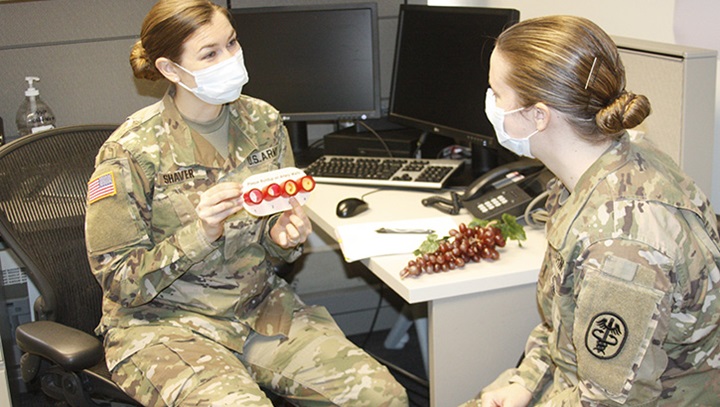 Image of Military health personnel wearing face mask while discussing food options .