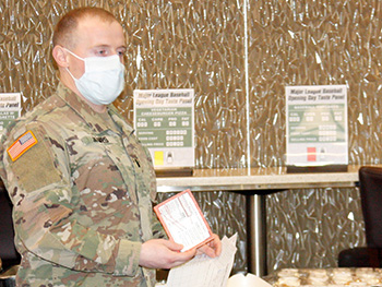 Military personnel wearing a face mask giving a presentation on food options