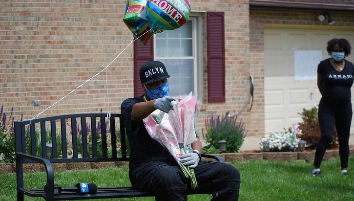 Image of soldier sitting on a bench with flowers and a balloon. Click to open a larger version of the image.