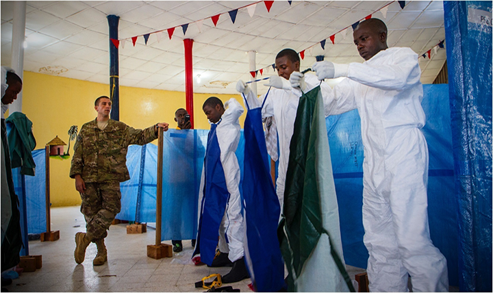 U.S. Air Force Senior Airman Joshua Douglass, left, an aerospace medical technician, watches as Liberian health care workers properly put on their personal protective equipment as part response by the Defense Department operation to provide logistics, training and engineering support during the Ebola virus outbreak. (U.S. Army photo by Staff Sgt. Terrance D. Rhodes)