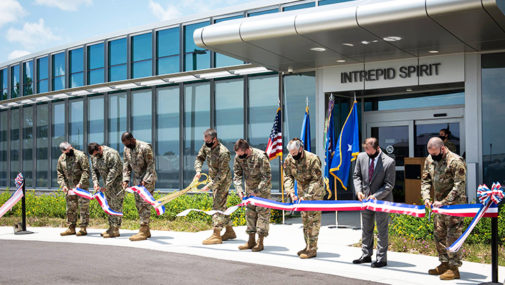 Image of Soldiers holding a long ribbon and cutting it.