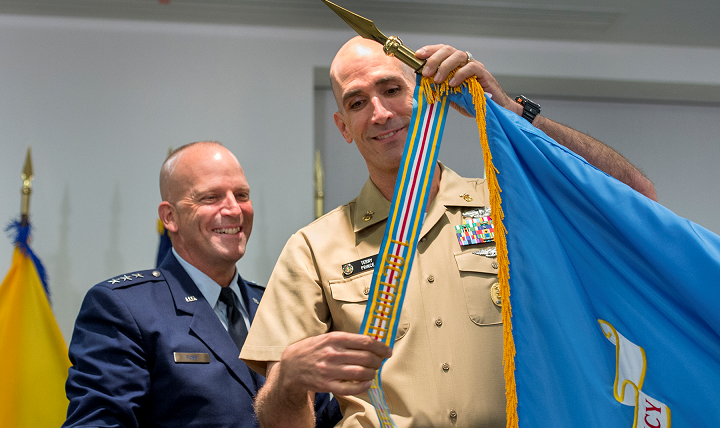 Air Force Lt. Gen. (Dr.) Douglas J. Robb, director of the Defense Health Agency, watches as Navy Master Chief Petty Officer Terry Prince attaches the Meritorious Unit Award streamer to DHA’s unit flag in Falls Church, Va., Oct. 1, 2015. The award ceremony coincided with DHA's second anniversary and the organization achieving full operating capability. DoD photo by EJ Hersom