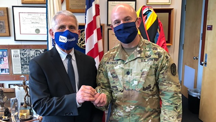Image of Two men in masks; one a military soldier, and the other wearing a suit. Click to open a larger version of the image.