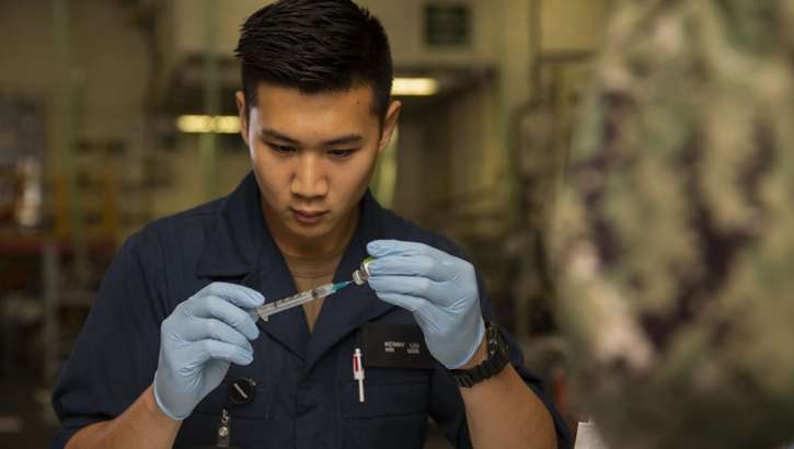 Navy Hospital Corpsman Kenny Liu, from San Jose, assigned to USS Gerald R. Ford's medical department, prepares a needle with a flu vaccination in the ship's hangar bay. (U.S. Navy photo by Mass Communication Specialist Seaman Apprentice Angel Thuy Jaskuloski)
