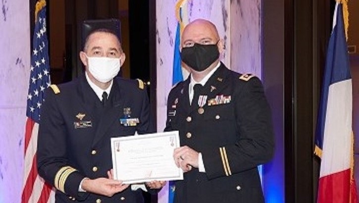 Image of Two military officers on stage; one handing the other a certificate. Click to open a larger version of the image.