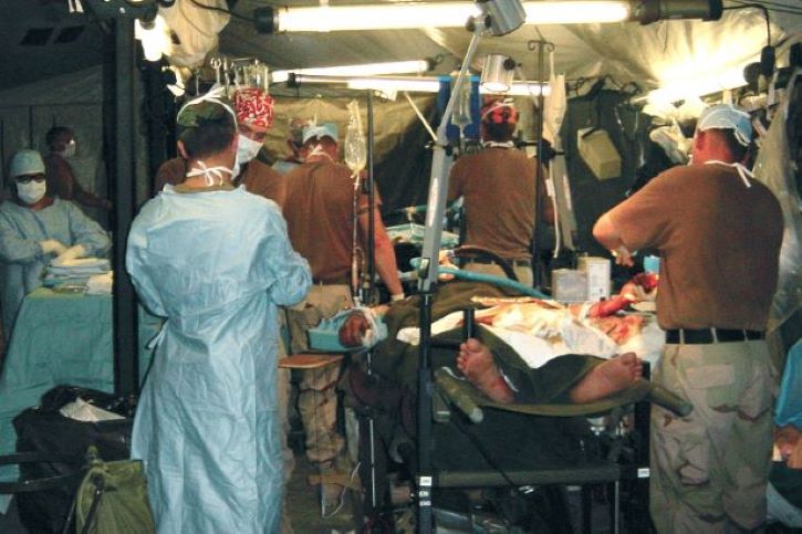 Military health personnel surrounding an operating table
