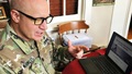 Military personnel sitting in front of laptop