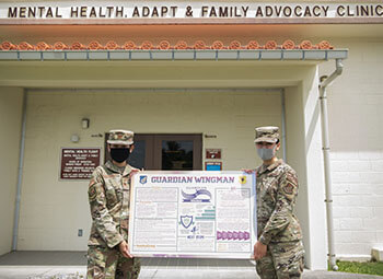 Military personnel standing in front of a Mental Health Adapt & Family Advocacy Clinic