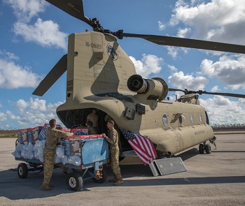 Military personnel unloading equipment from a helicopter