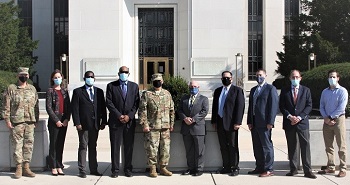 Group of men, wearing masks, standing in front of a building