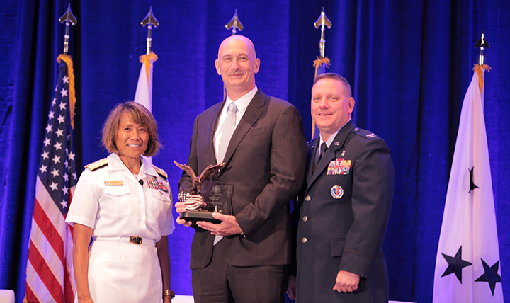 Vice Admiral Raquel C. Bono, director of the Defense Health Agency, presents the DHA/J-6 Field Grade Officer of the Year Award to Lieutenant Colonel (Ret.) Mark Mellott at the Defense Health Information Technology Symposium on July 25, 2017 in Orlando, Florida.