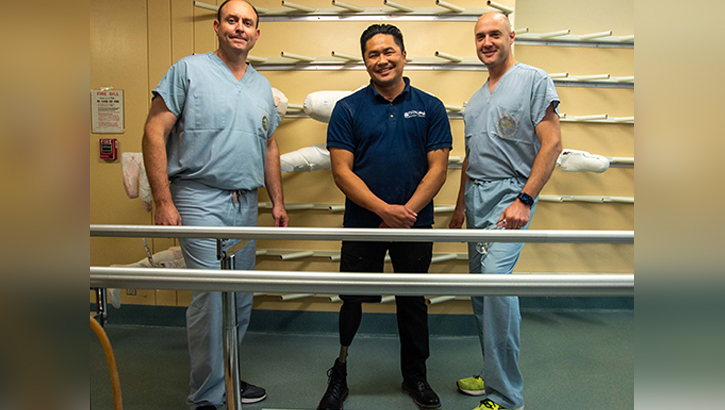  U.S. Navy Cmdr. Yan Ortiz-Pomales, specialty leader for plastic surgery in the U.S. Navy, left, Nathaniel Ortiz, lead prosthetist, center, and U.S. Navy Cmdr. James Flint, NMCSD orthopedic oncology surgeon, right, pose for a group photo
