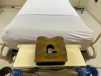 Image of a hospital bed with a platform with holes designed for a patient lying face down. 