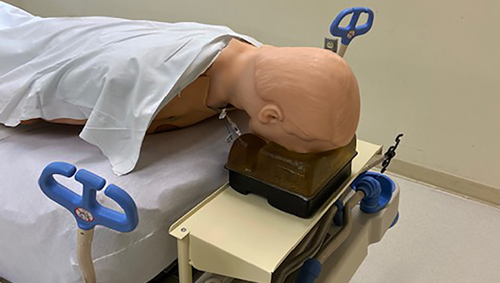 Image of a dummy laying face-down on a hospital bed