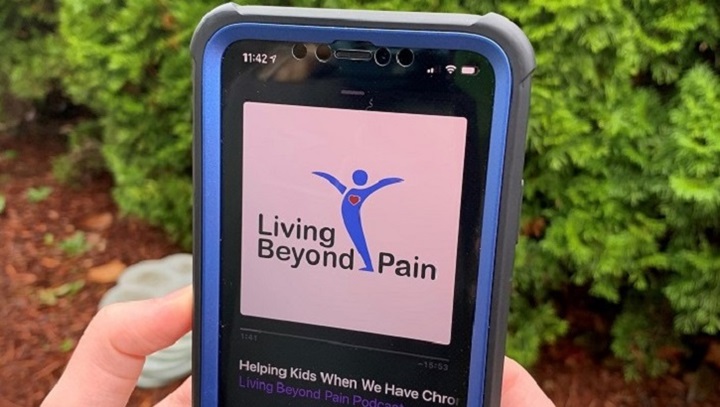 Image of Hands holding a smartphone with the Living Beyond Pain podcast playing on the device.
