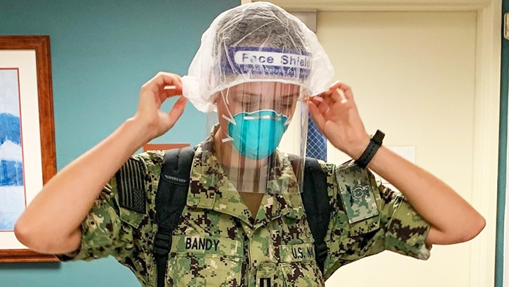 Military nurse putting on PPE
