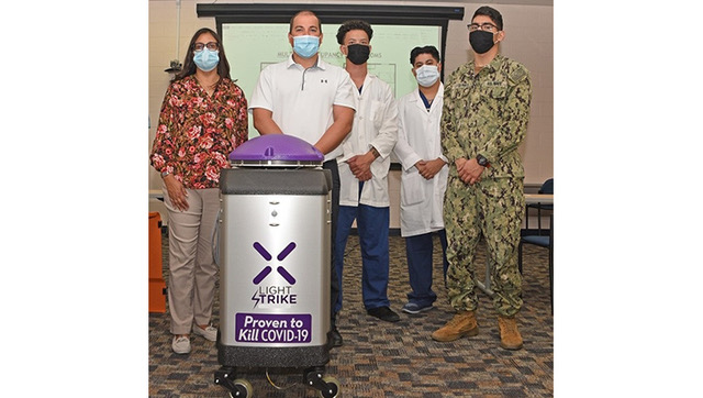 Image of Hospital personnel standing with a cleaning robot. Click to open a larger version of the image.