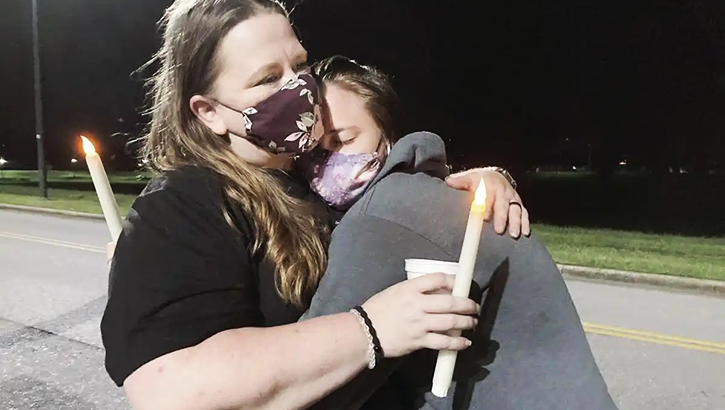 Image of Woman wearing a mask, hugging her daughter. Click to open a larger version of the image.