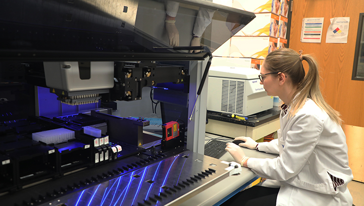 Image of Camille Alba of the Uniformed Services University's The American Genome Center, monitors the production of DNA libraries using the Microlab STAR precision liquid handling robot at USU. . Click to open a larger version of the image.