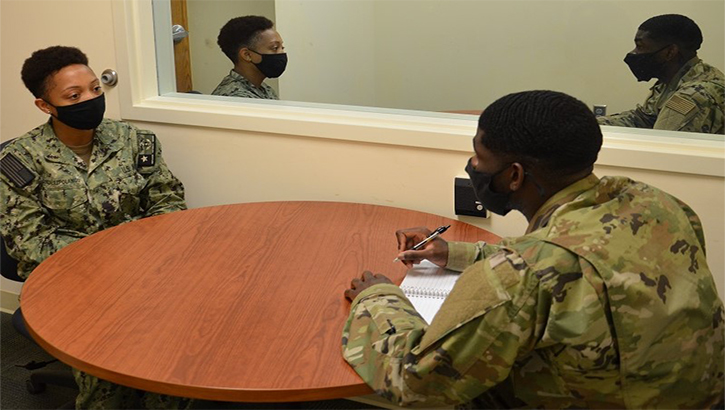 Image of Two servicemembers talking at a table. Click to open a larger version of the image.