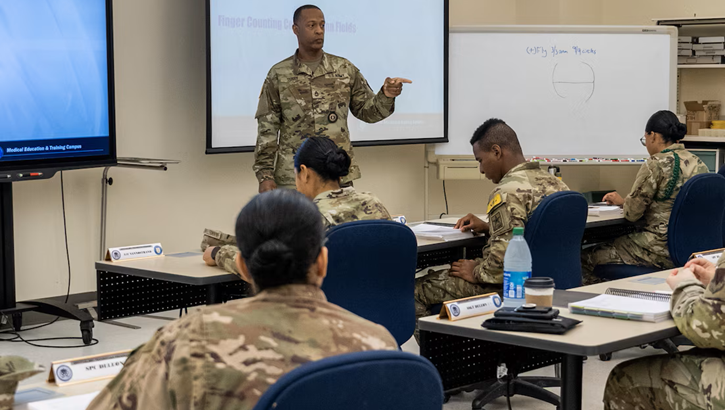 An instructor with the Medical Education and Training Campus addresses service members during a classroom session.