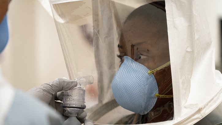 Image of soldier in a hazmat suit with a medical-grade mask.