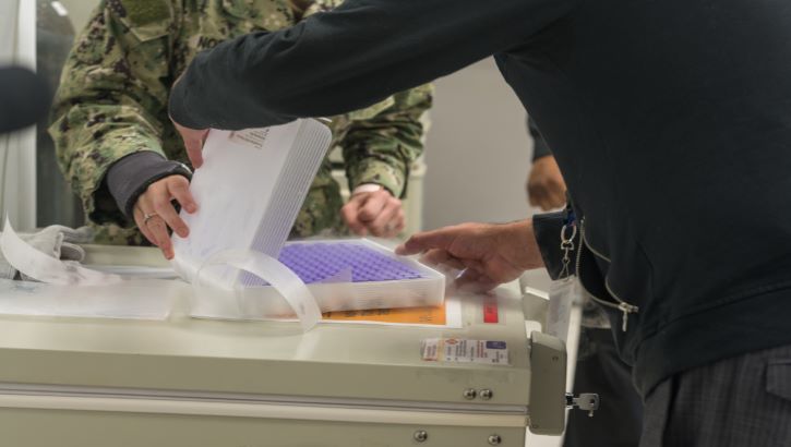 Image of military personnel getting COVID-19 vaccines ready. Click to open a larger version of the image.