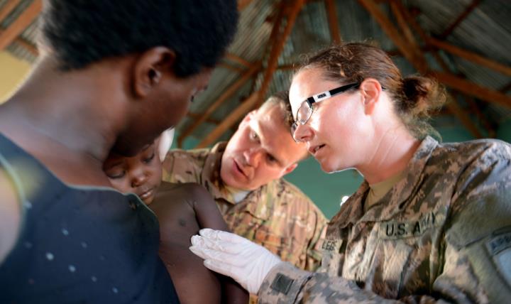U.S. Army Capt. Courtney Legendre, a physician assistant with the 411th Civil Affairs Battalion in support of Combined Joint Task Force-Horn of Africa, examines a child with the help of U.S. Air Force Maj. Andrew A. Herman, a medical planner in the CJTF-HOA Surgeon Cell in Kakute, Uganda, April 23, 2013. (Photo by U.S. Navy Petty Officer 1st Class Tom Ouellette)
