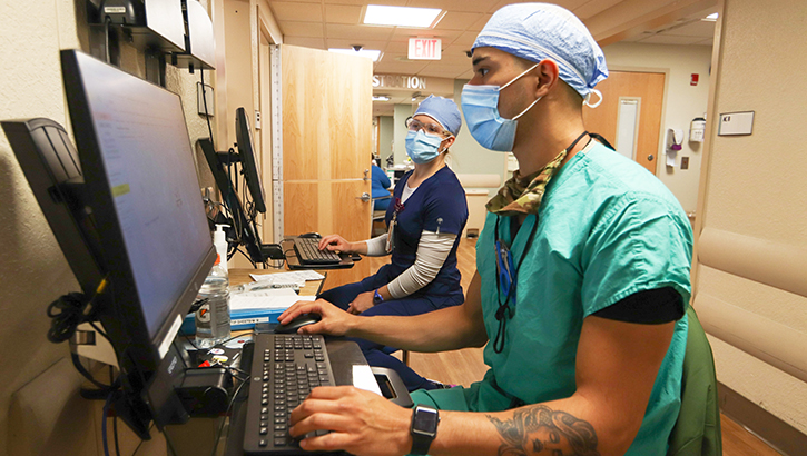 Medical technicians wearing masks and entering information on a computer
