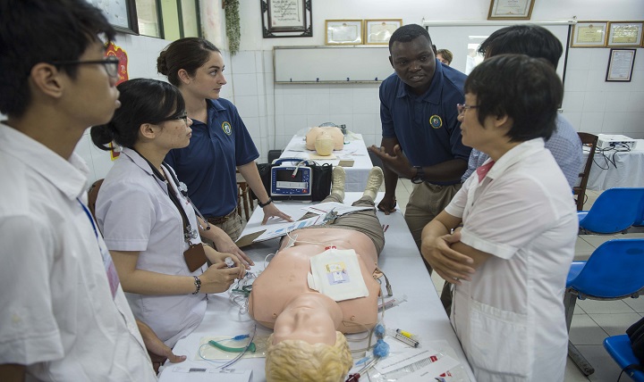 Navy Ensign Christine Harrington (left) and Hospital Corpsman 2nd Class Harrison Mwanzi, from the hospital ship USNS Mercy, explain the procedures for treating cardiac arrest at an advanced cardiovascular life support subject matter expert exchange at Da Nang Central Hospital during Pacific Partnership 2015. 
