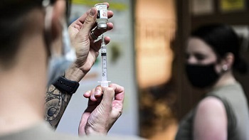 Military health personnel filling a syringe with the COVID-19 vaccine